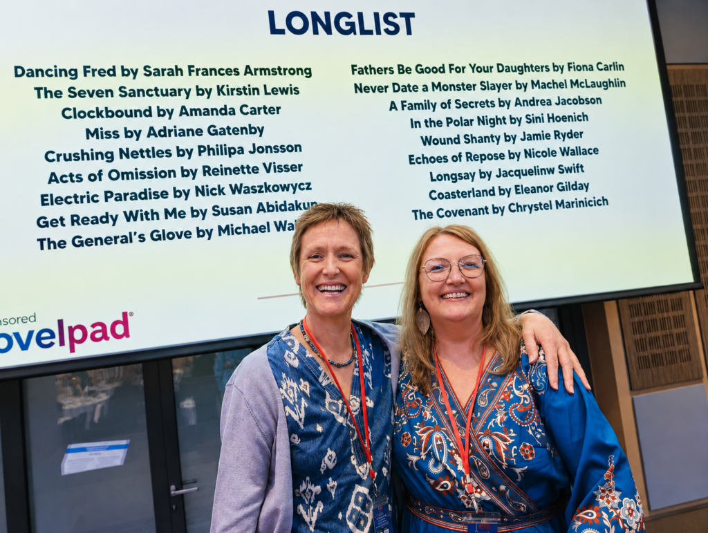 Reinette Visser and Nicole Wallace in front of the board displaying their longlisting