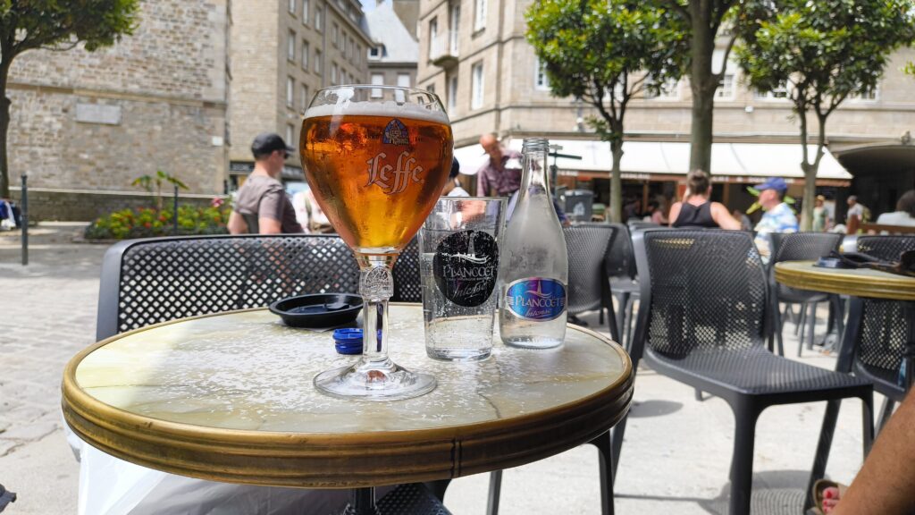A glass of beer on a table. St Malo old town in the background.